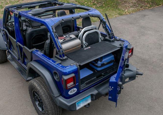 Side view of black EZTrunk installed with items inside cargo area of Jeep Wrangler with trunk door open, showing storage use.
