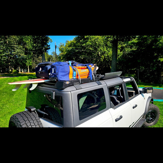 White Ford Bronco with heavy-duty roof rack in rocky terrain, showing durable off-road cargo storage for adventure use.