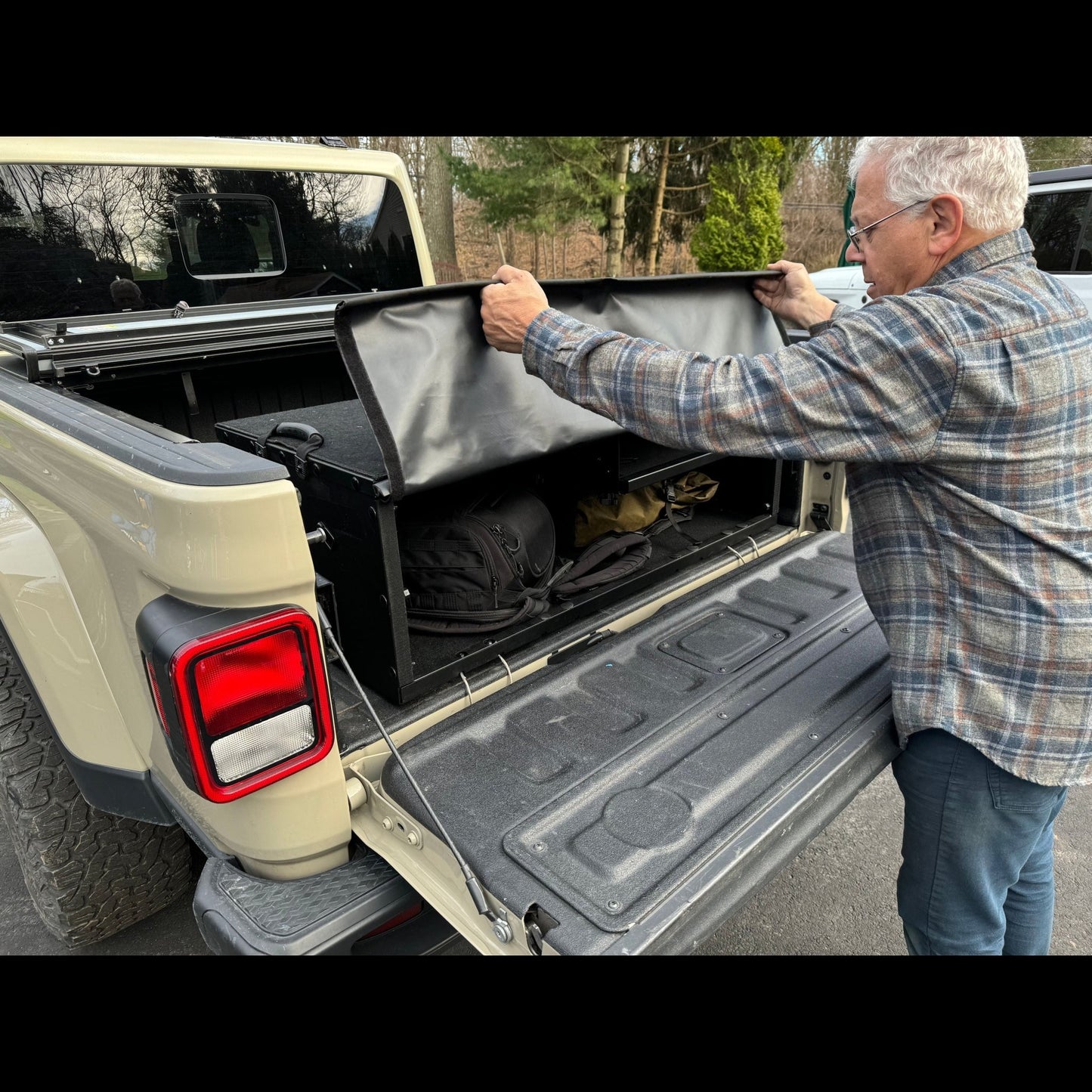 Man closing EZ Quickbox filled with gear, showcasing spacious, secure cargo area ideal for organized truck bed storage.