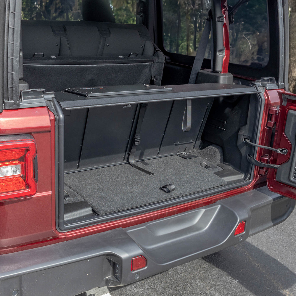 Side view black EZTrunk installed in cargo area of red Jeep Wrangler with trunk door open, showing secure storage setup.