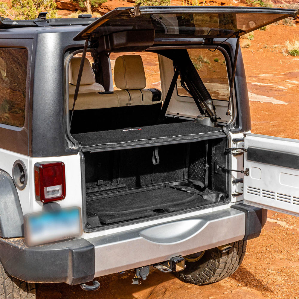 Side view black EZTrunk installed in cargo area of white Jeep Wrangler with trunk door open, showing secure storage setup.