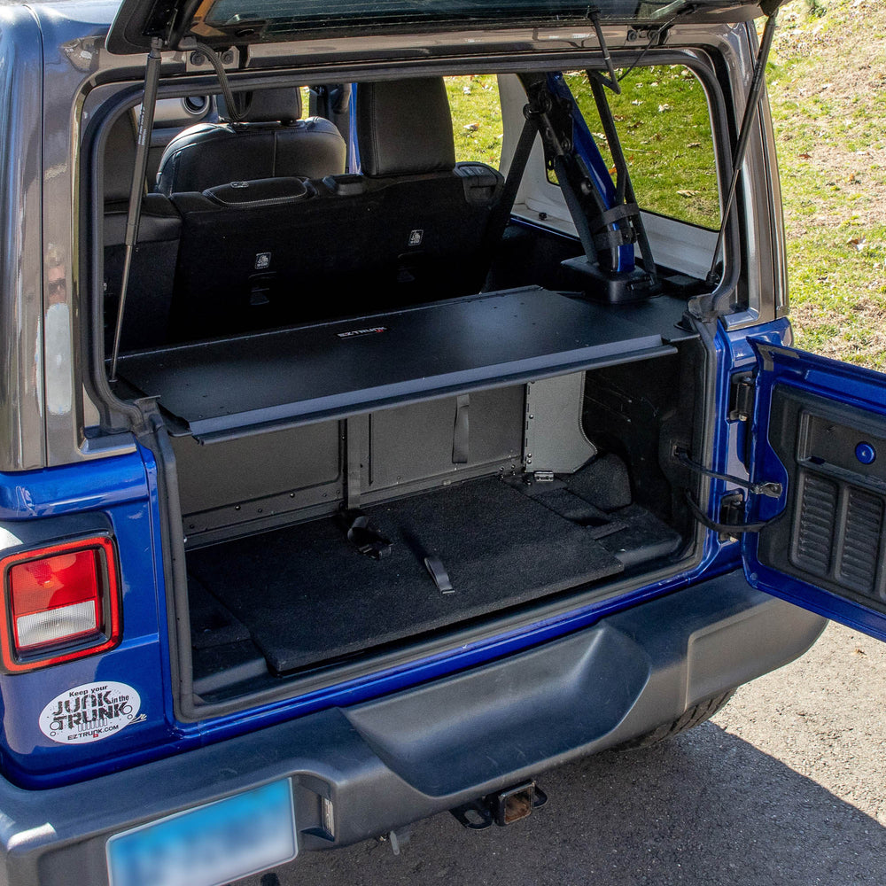 Black EZTrunk installed in blue Jeep Wrangler, shown empty to highlight spacious, secure aftermarket cargo storage solution.