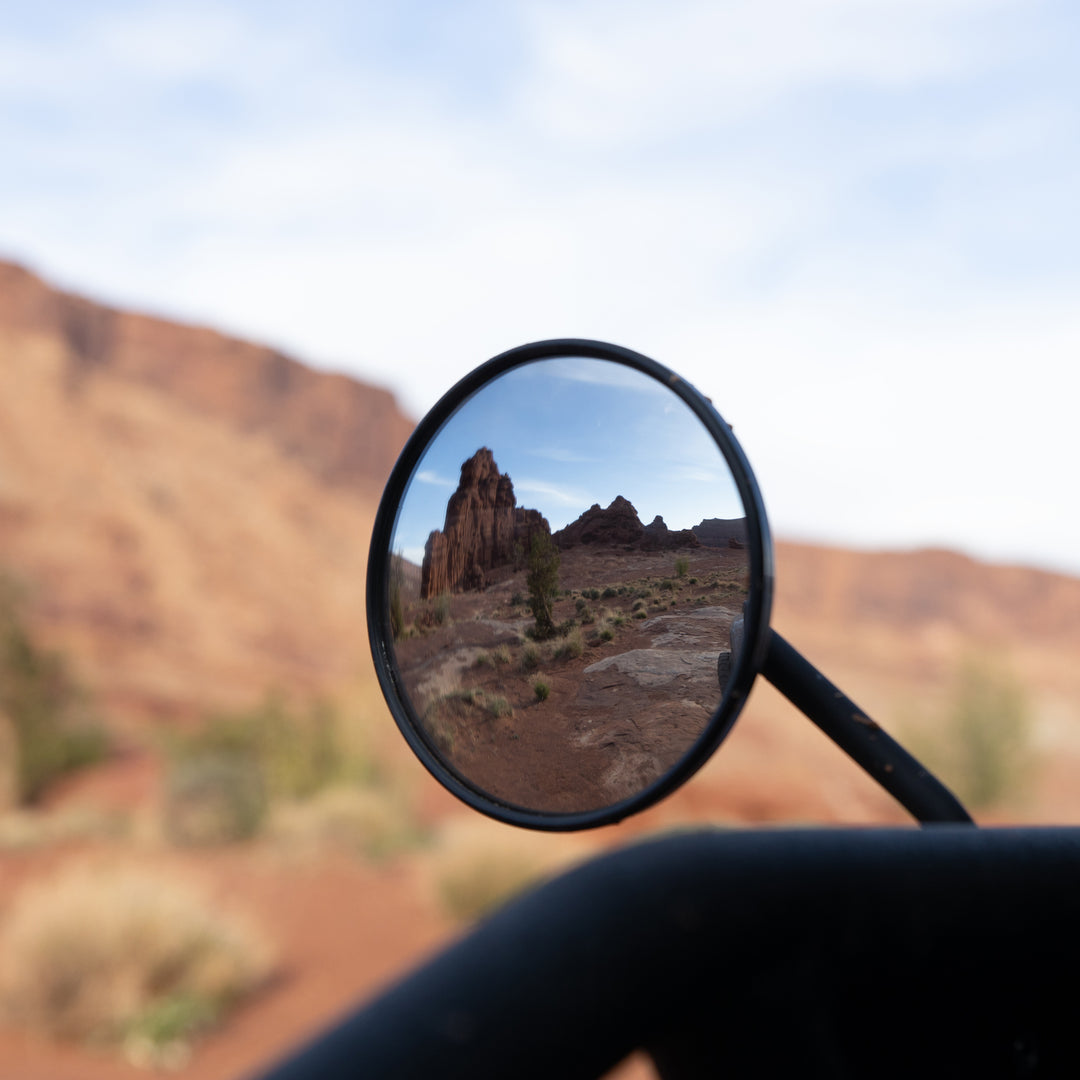 Round aluminum side mirror designed for Jeep Wrangler and Gladiator, shown mounted, offering durable aftermarket upgrade.