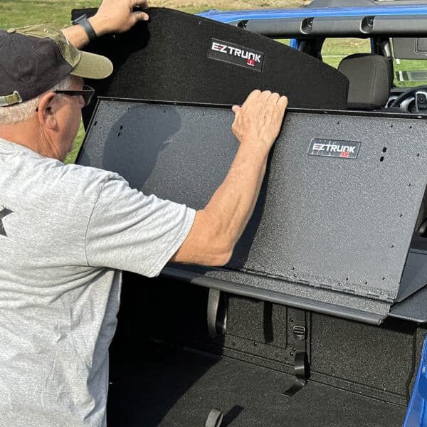 Man folding EZTrunk Extension Table forward and adding black carpet, showing setup process and enhanced cargo protection.