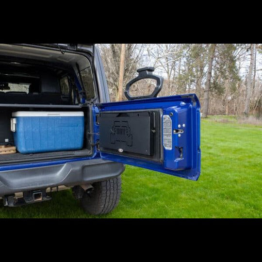Tailgate table installed on Jeep shown folded up, highlighting space-saving design ideal for off-roading and camping.