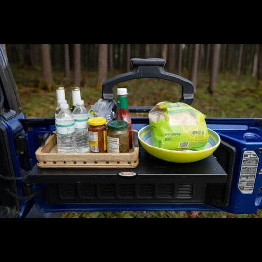 Aftermarket black foldable tailgate table mounted on Jeep, shown holding food and drinks—perfect for camping and tailgating.