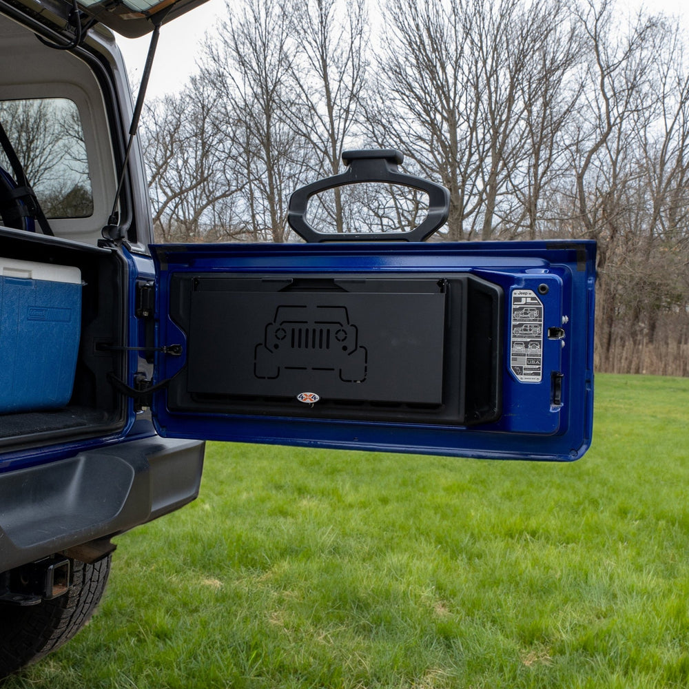 Tailgate table installed on Jeep shown folded up, highlighting space-saving design ideal for off-roading and camping.