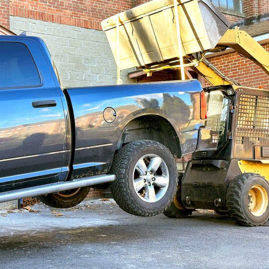 Dump truck lifting Ram truck bed using Truck Buddiez bed anchor straps, showcasing heavy-duty strength and secure lifting.