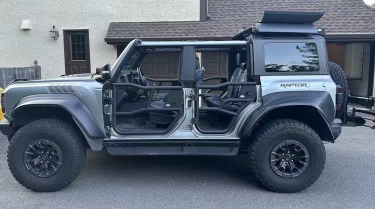 Gray four-door Ford Bronco Raptor with EZ4X4 Alpha Tube Doors, EZ4X4 EZFlipTop, and roof rack parked outdoors.