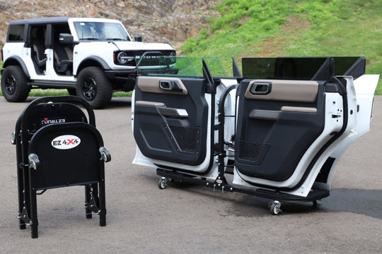 White Ford Bronco with doors stored on EZ4X4 door carts; second cart folded for compact, easy transport on driveway.