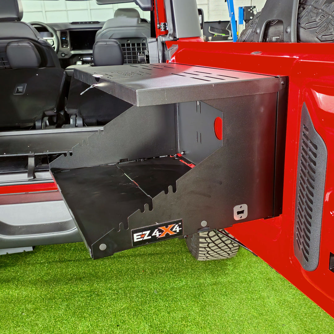 Side view of the EZ4X4 Extreme Tailgate Table fully opened and installed on the tailgate of a red Ford Bronco.