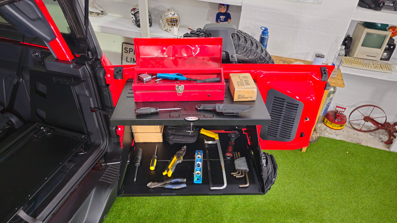 EZ4X4 Extreme Tailgate Table installed on a red Ford Bronco with a toolbox, screwdrivers and other tools spread across the table surface and lower shelf.