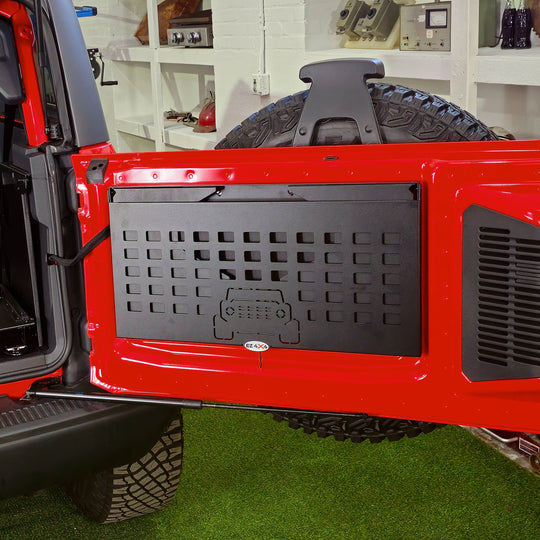EZ4X4 Extreme Tailgate Table with MOLLE top folded compactly and installed on the tailgate of a red Ford Bronco.