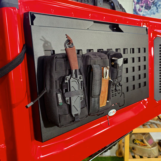 EZ4X4 Extreme Tailgate Table for Ford Bronco folded on the tailgate, with MOLLE top holding pouches and gear.