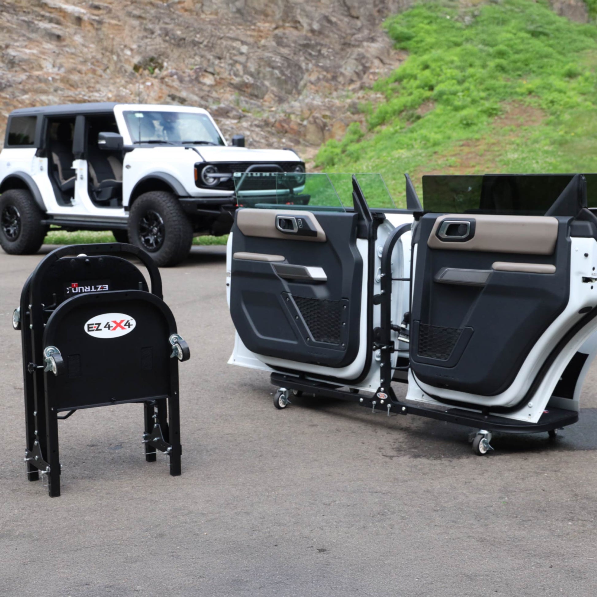 Ford Bronco parked beside EZ4X4 Rolling Door Carts displaying four stored doors, with one cart folded for transport.