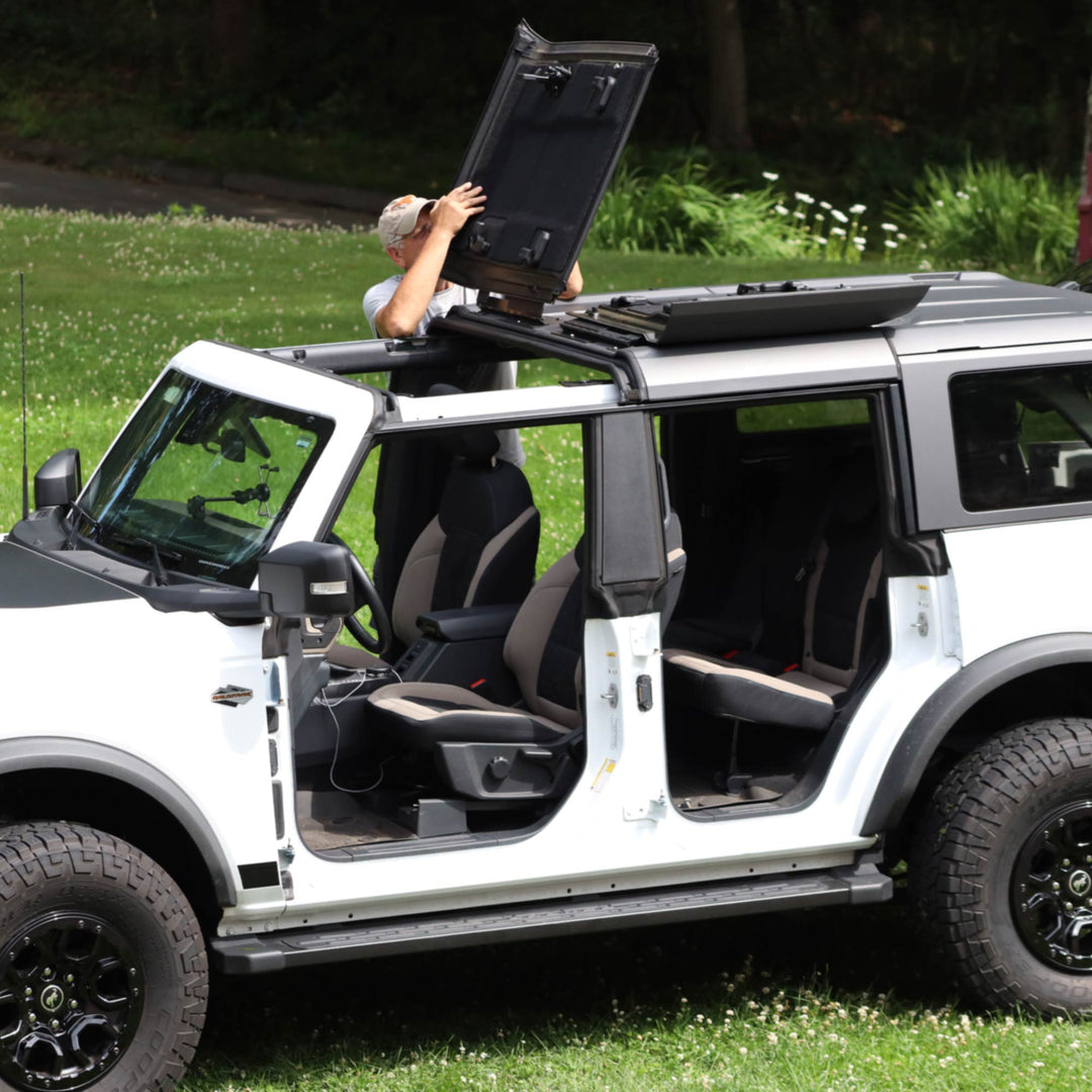 White Ford Bronco with a man flipping and securing the front roof panels using the EZ4X4 EZ FlipTop system.
