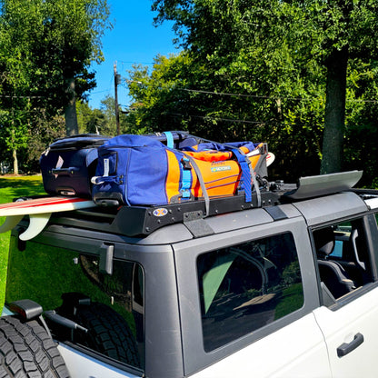 White Ford Bronco with an EZ4X4 Middle Panel Roof Rack carrying luggage, a duffel bag, and a surfboard.