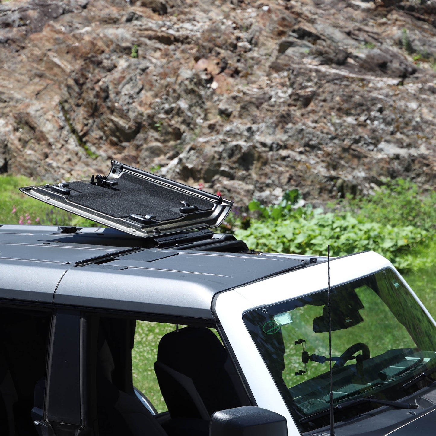 White Ford Bronco with flip-top panels fully open, showing roof flipped up for ventilation and off-road driving.