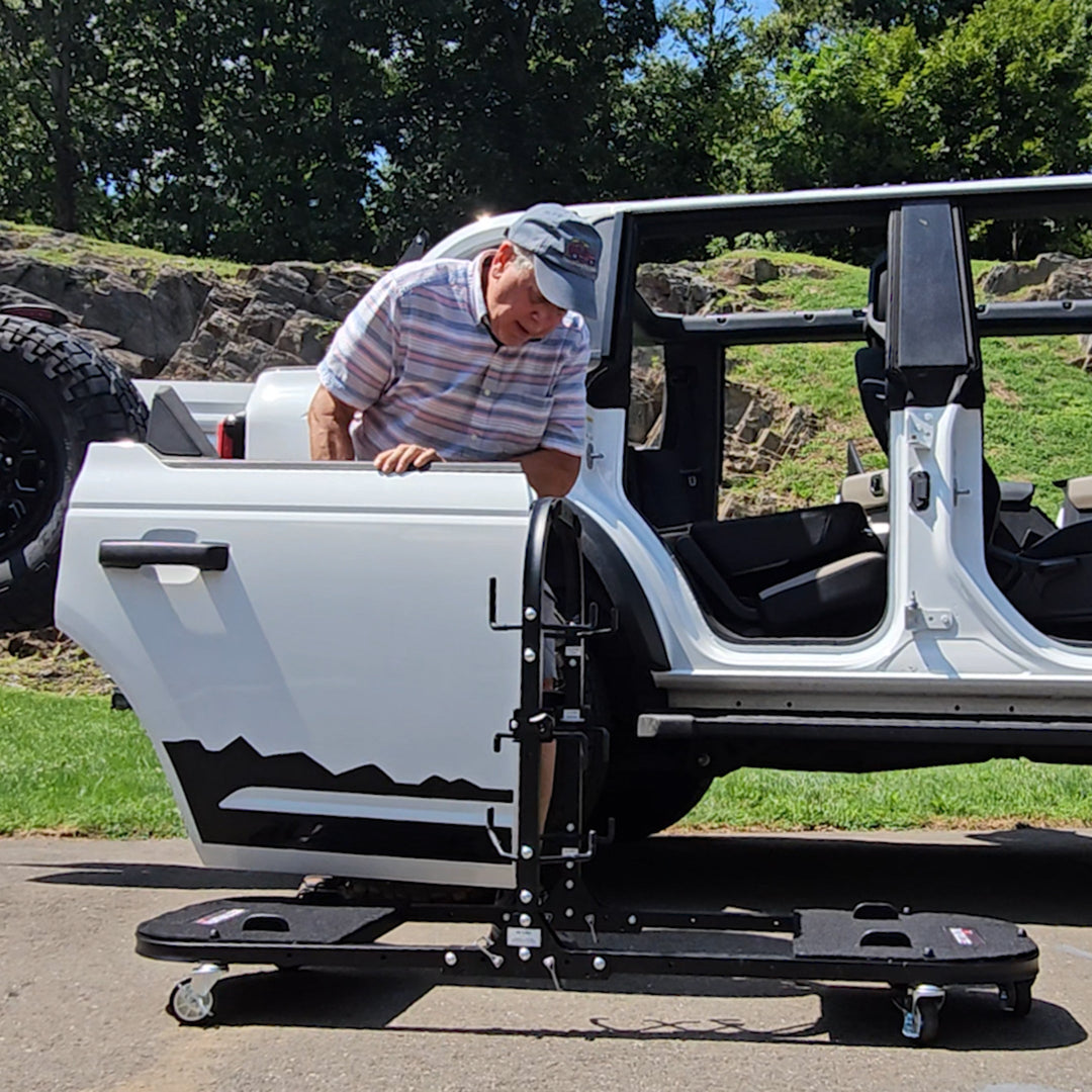 Man loading white Jeep doors from vehicle onto EZ4X4 door cart, showing easy, secure storage and transport setup.