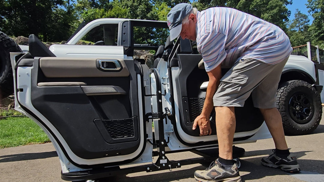 Man finishing loading all four white Jeep doors onto EZ4X4 door cart, showing secure storage and easy transport setup.