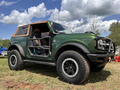 Green Ford Bronco with aluminum full tube doors in natural setting, highlighting rugged off-road style and durability.