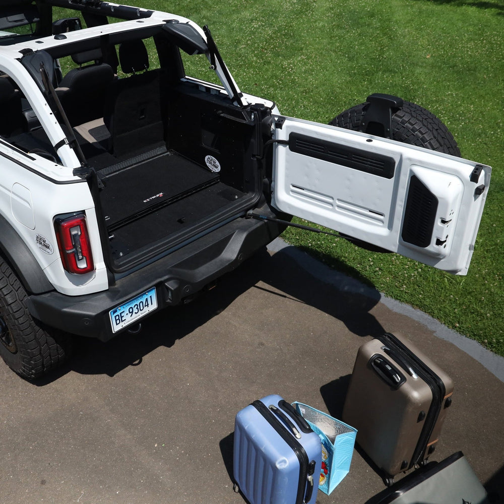 White Bronco with Extreme EZTrunk folded for compact storage, luggage placed outside vehicle, showing travel readiness.