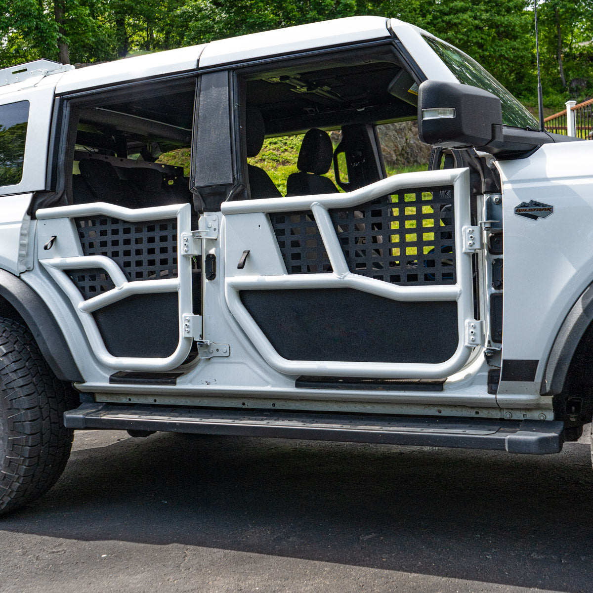 Side view of a white four-door Ford Bronco with color-matched Alpha Tube Doors and black MOLLE panels.