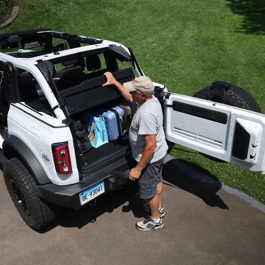 Man closing Extreme EZTrunk with luggage stored inside white Bronco, showing secure, organized cargo storage.