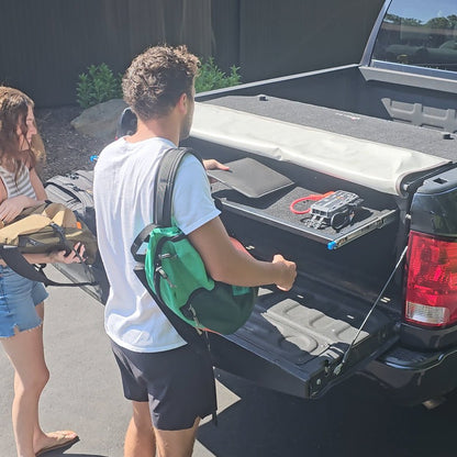 Two people organizing gear with a shelf inside the black EZ Trunk, showcasing versatile cargo storage and space optimization.