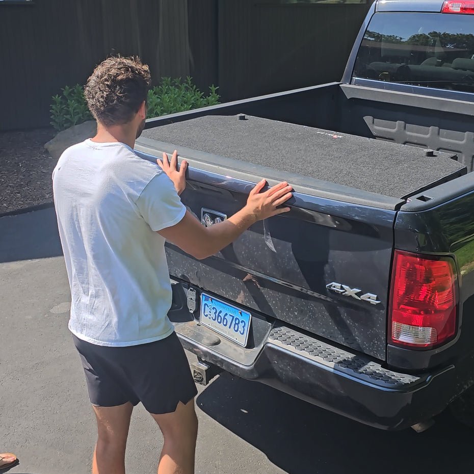 Man closing tailgate of black Ram pickup with black EZ Trunk secured inside, showcasing secure fit and organized cargo space.