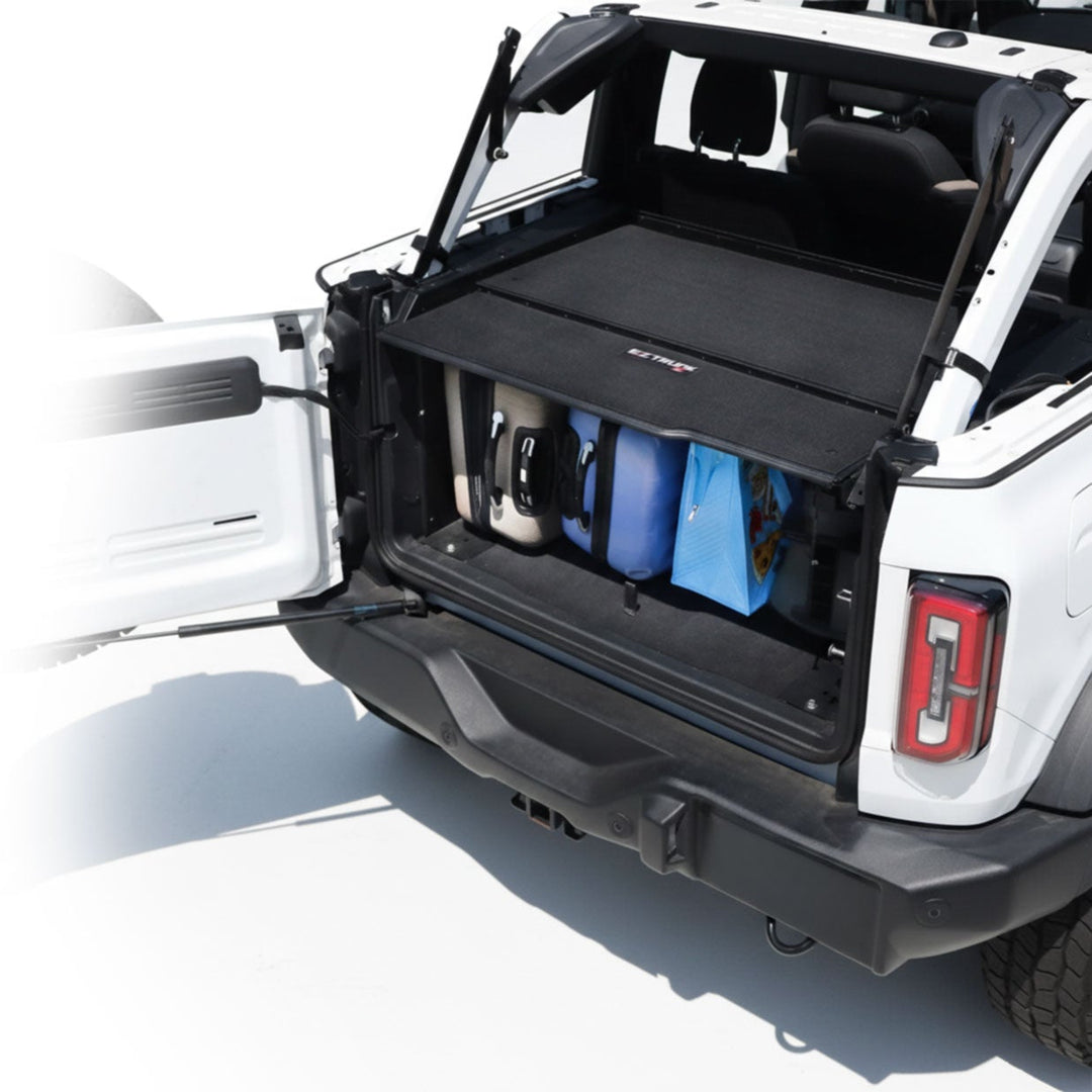 EZ4X4 Extreme EZTRUNK installed in a white Jeep Wrangler, shown with luggage stored securely in the open cargo area.