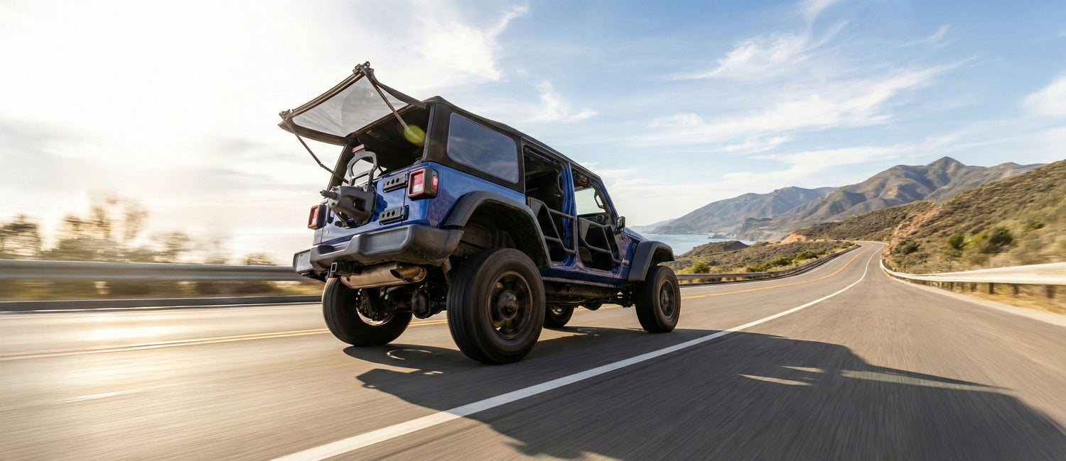 EZ4X4 EZWindow and Razor Tube Doors on blue Jeep Wrangler driving on a coastal highway.