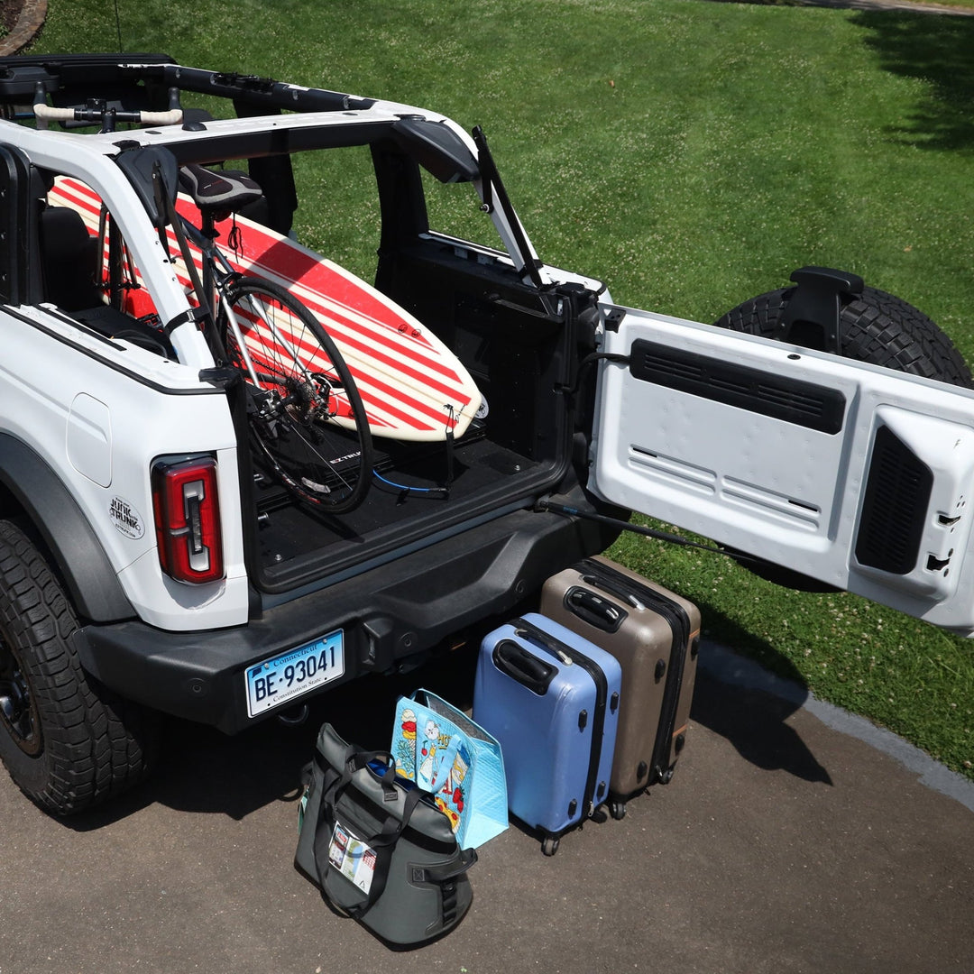 Extreme EZTrunk flattened with surfboard and bicycle inside white Bronco, showing versatile and spacious cargo storage.