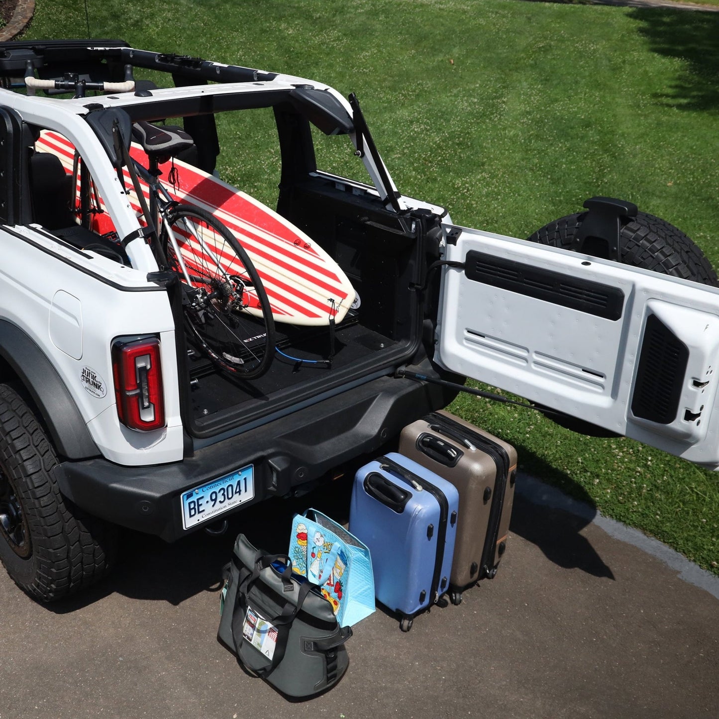 Extreme EZTrunk flattened with surfboard and bicycle inside white Bronco, showing versatile and spacious cargo storage.