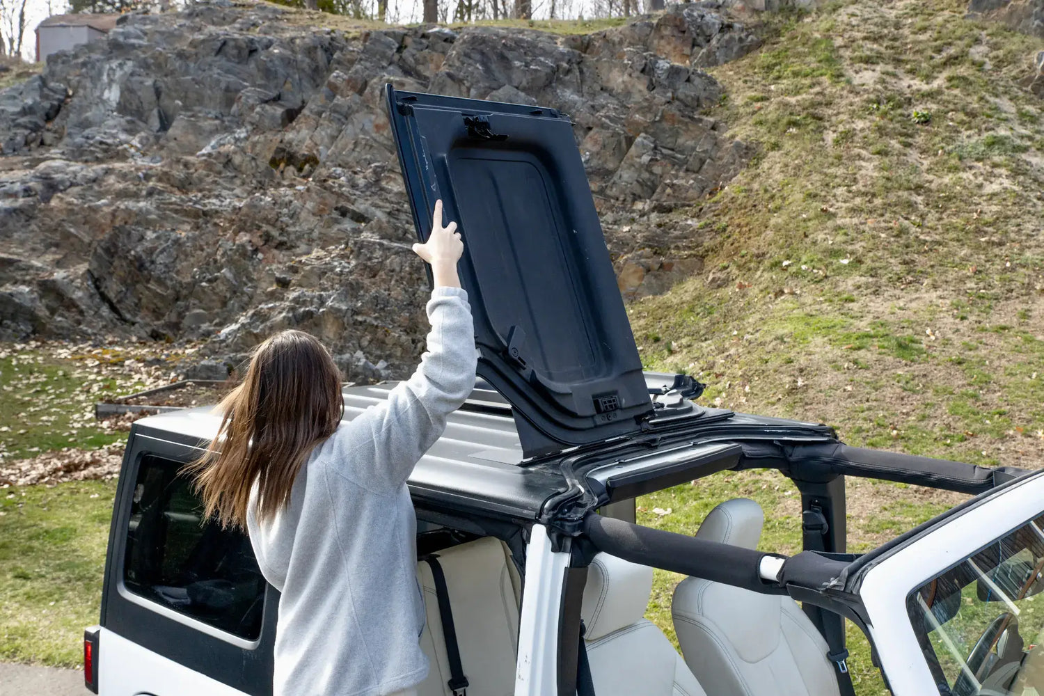 Woman flipping a Freedom Panel back on a white Jeep Wrangler using the EZ4X4 EZ FlipTop.