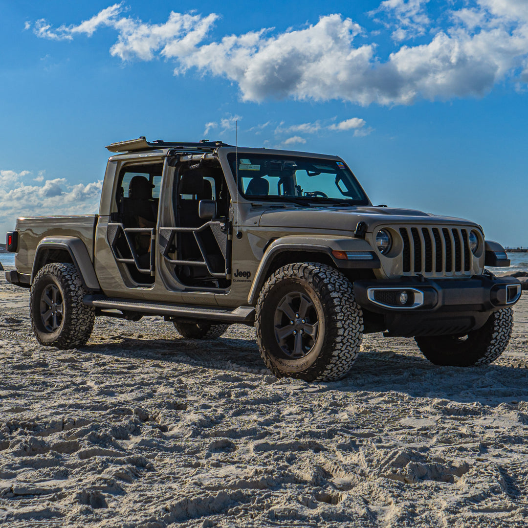 Tan Jeep Gladiator parked on a sandy beach featuring black EZ4X4 Razor Tube Doors and the EZ FlipTop securing the open freedom panels.