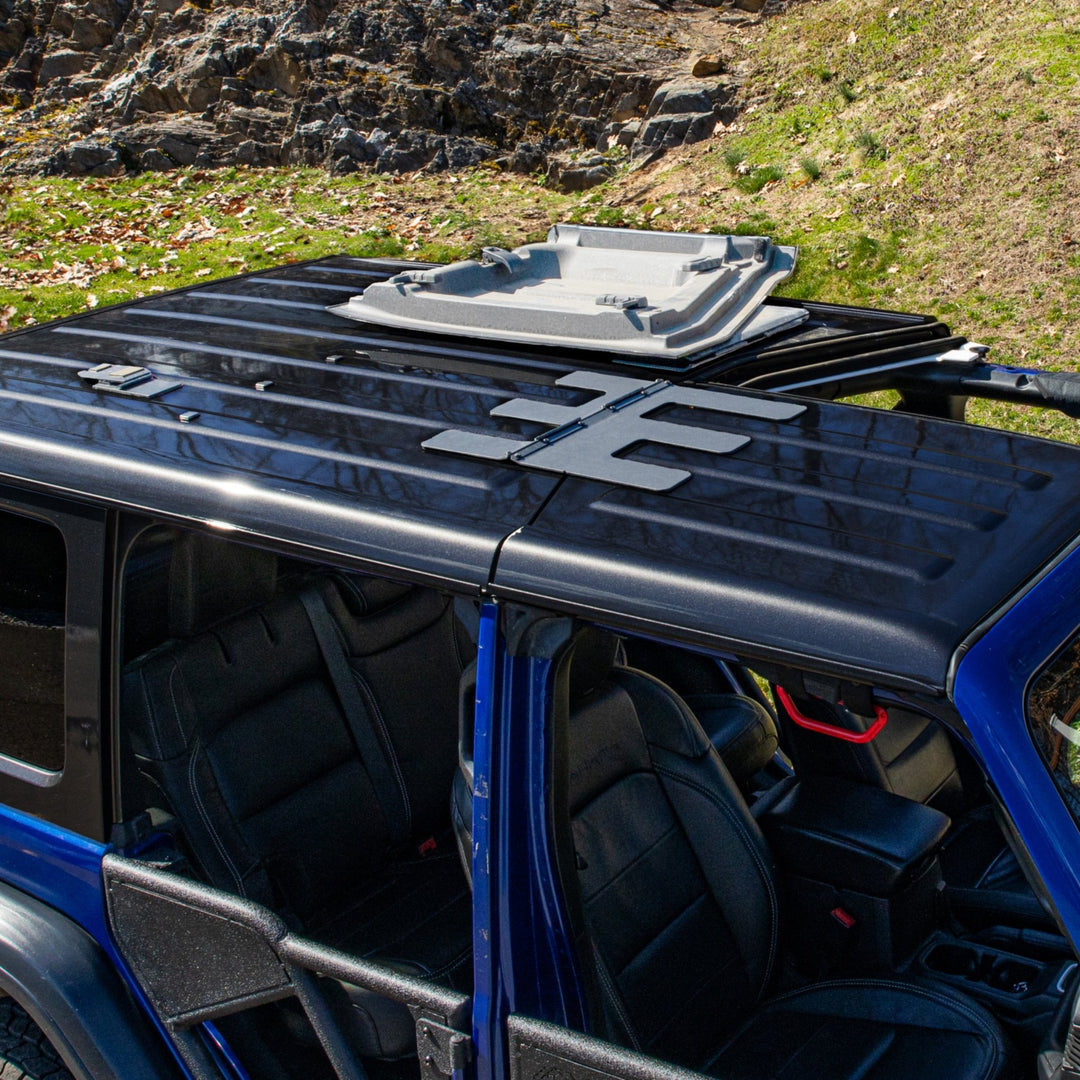 Overhead view of a blue Jeep Wrangler showing the EZ4X4 EZ FlipTop system with one Freedom Panel locked open and the other still attached.