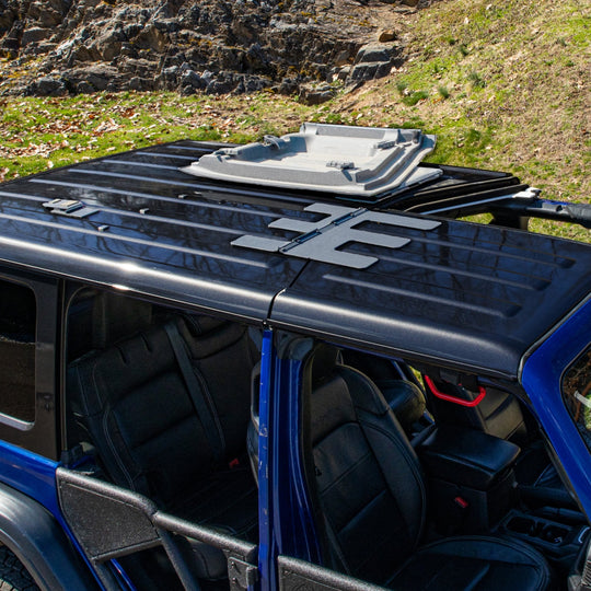 Overhead view of a blue Jeep Wrangler showing the EZ4X4 EZ FlipTop system with one Freedom Panel locked open and the other still attached.