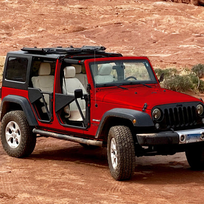 Red Jeep with Freedom Panels flipped up and black aluminum Phantom tube doors, showcasing rugged off-road upgrades.