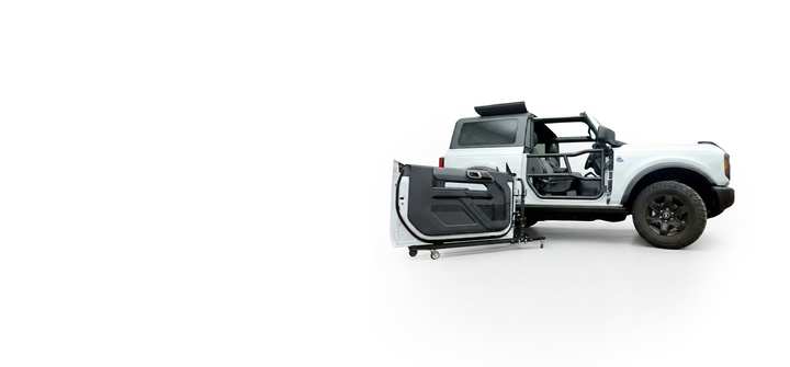 White 2-door Ford Bronco with black EZ4X4 Alpha Tube Doors installed and OEM doors stored in front on the EZ4X4 Door Cart. 