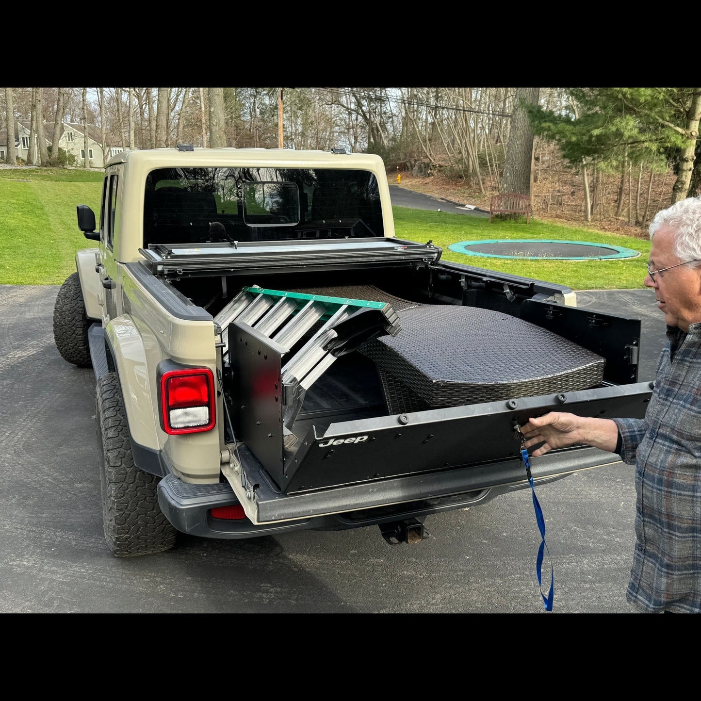 Man securing cargo in Jeep Gladiator JT truck bed using EZ4X4 tailgate extender, showing added space and secure transport.