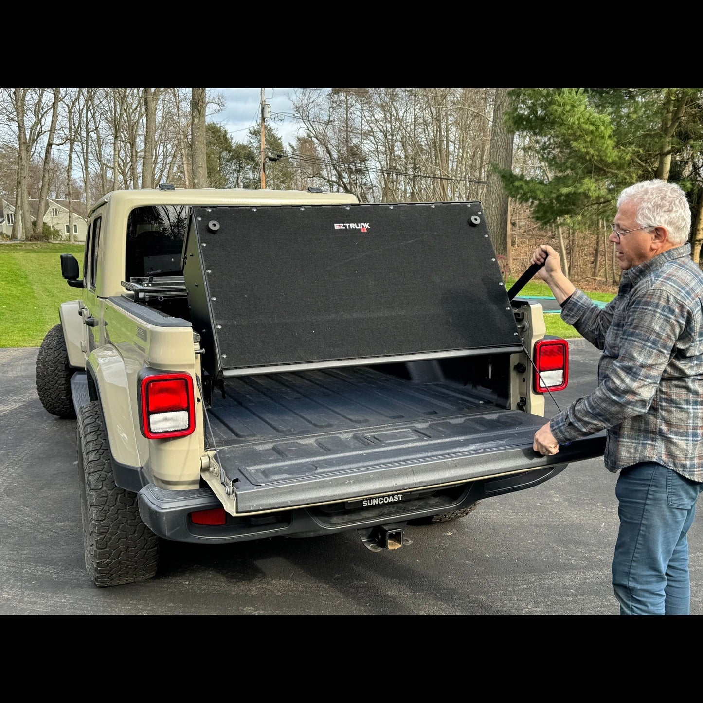 Man using handle to convert EZ4X4 Bed Box in Jeep Gladiator JT from secure storage to tailgate extension.