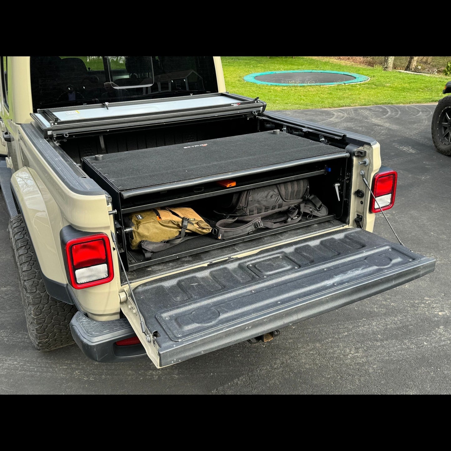 EZ4X4 Bed Box installed in Jeep Gladiator, shown with tailgate down and packed gear, highlighting secure truck bed storage.