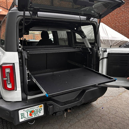 Angled view of a white Ford Bronco with rear window open and the EZ4X4 Extreme EZTRUNK shelf fully extended and empty.