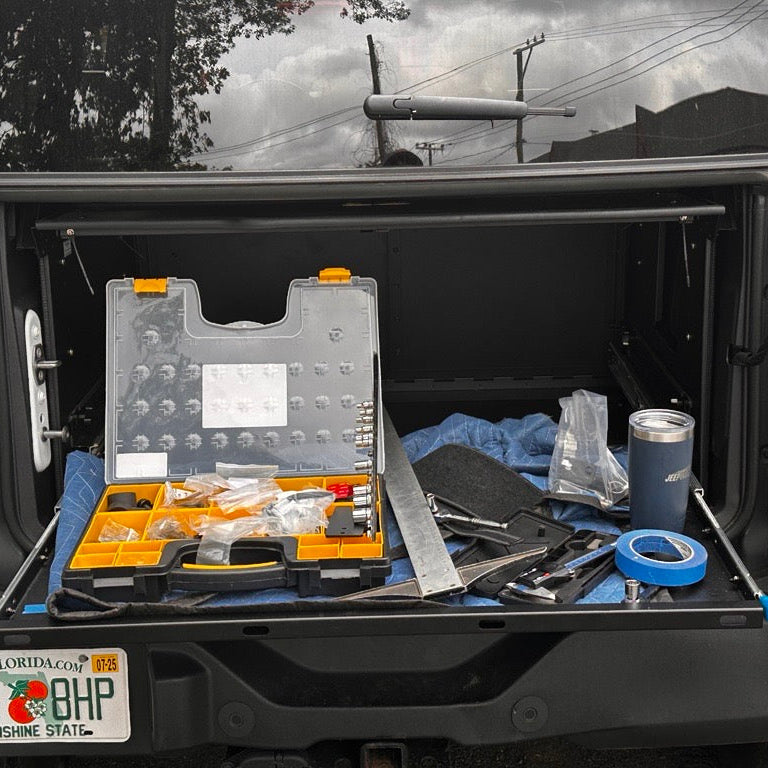 Close-up front view of the EZ4X4 Extreme EZTRUNK sliding shelf fully extended, holding tools and used as a work surface.