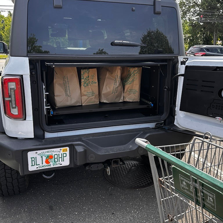 White Bronco with groceries stored securely on the EZ4X4 Extreme EZTRUNK sliding shelf.