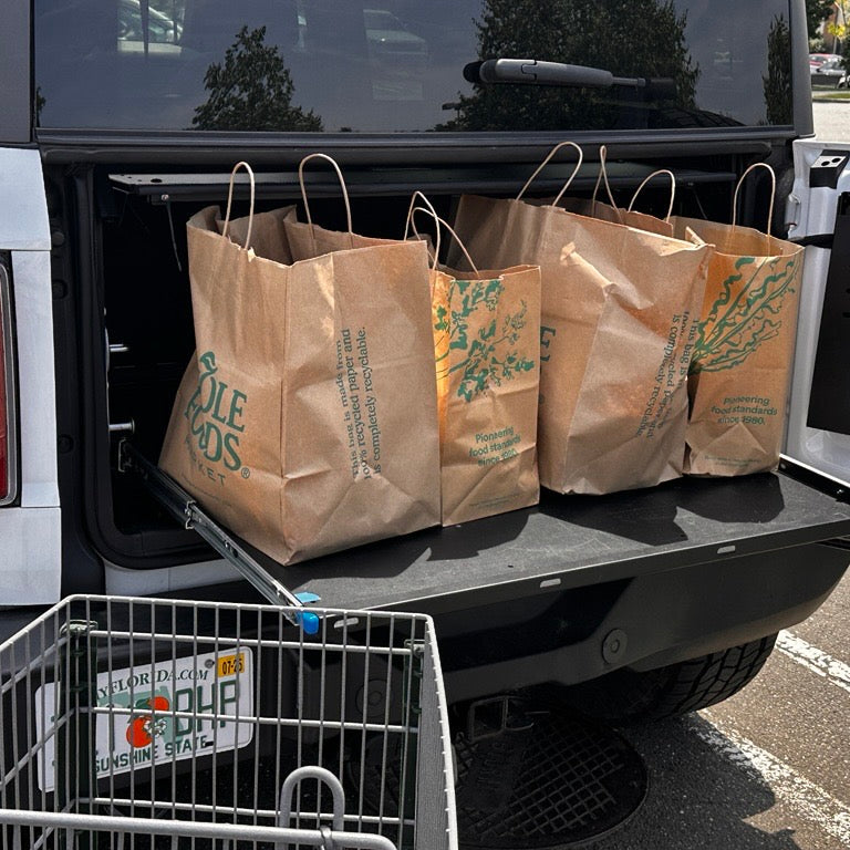 White Ford Bronco cargo area with EZ4X4 Extreme EZTRUNK and sliding shelf extended holding brown grocery bags.