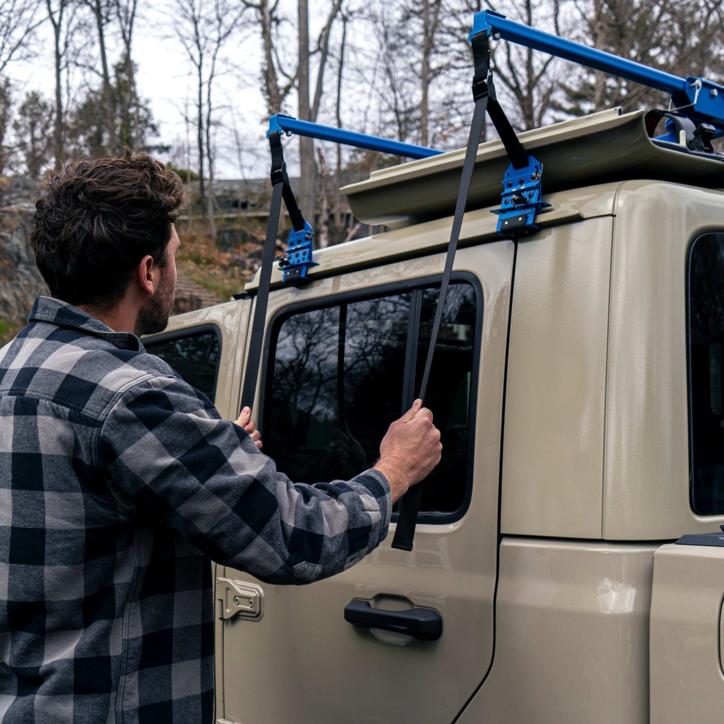 Man in a plaid shirt securing the straps of the EZ4X4 Hard Top Remover Lift while lifting the hardtop from a beige Jeep Gladiator (JT).