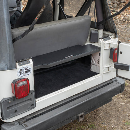 Black EZTrunk installed in cargo area of white Jeep TJ Wrangler with trunk door open, showing secure storage setup.