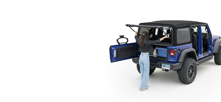 Woman securing the rear soft top window of a blue Jeep Wrangler using EZ4X4 EZ Window Support Arms.